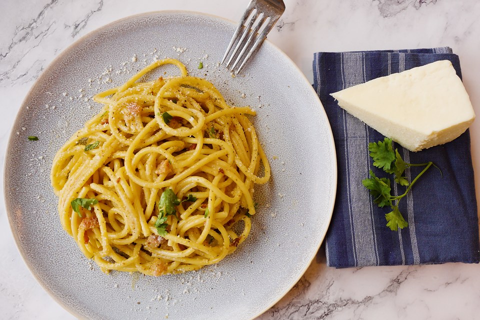 Carbonara with pecorino and parsley on a pale marble surface